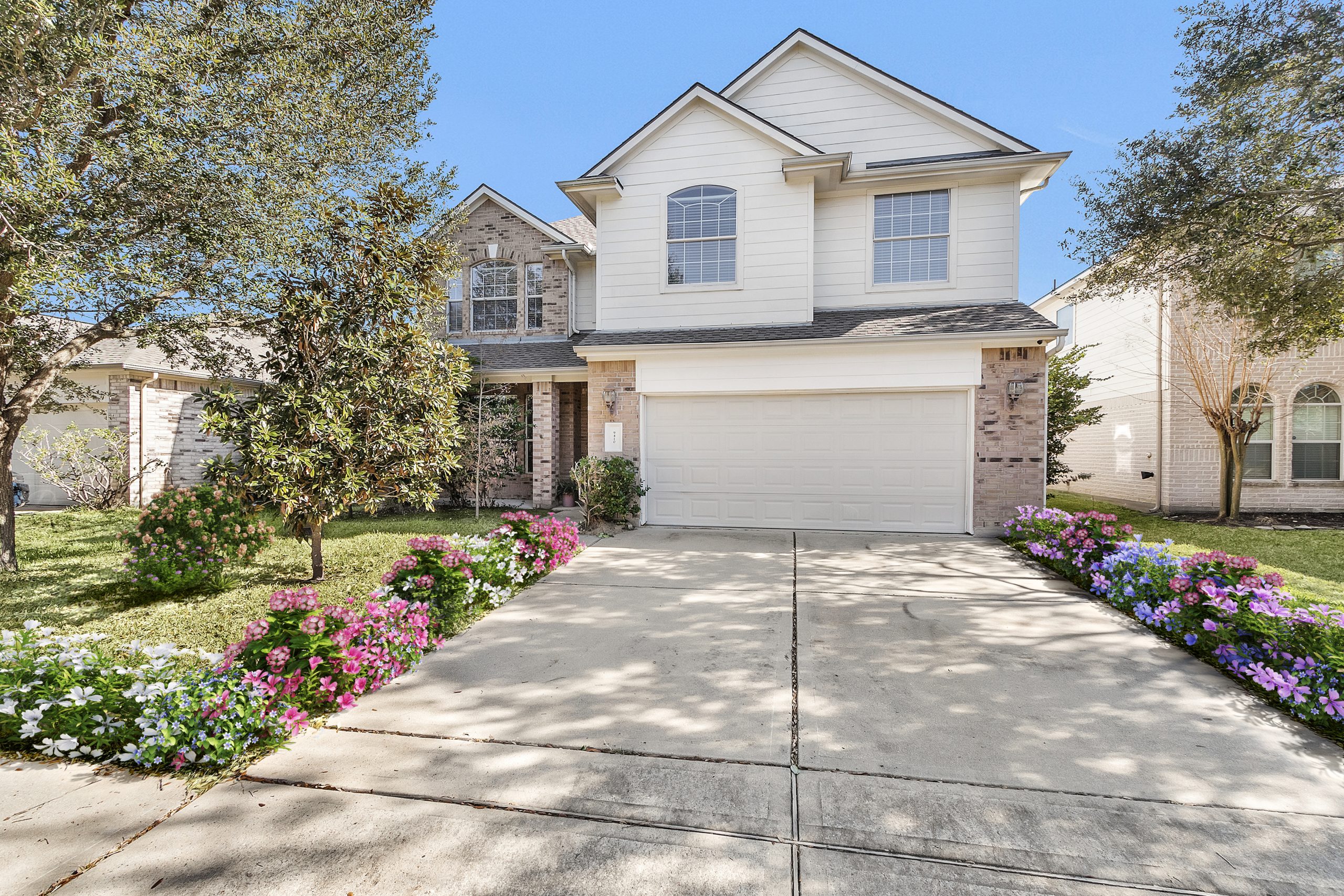 Front yard of a residential home with bright floral virtually staged landscaping