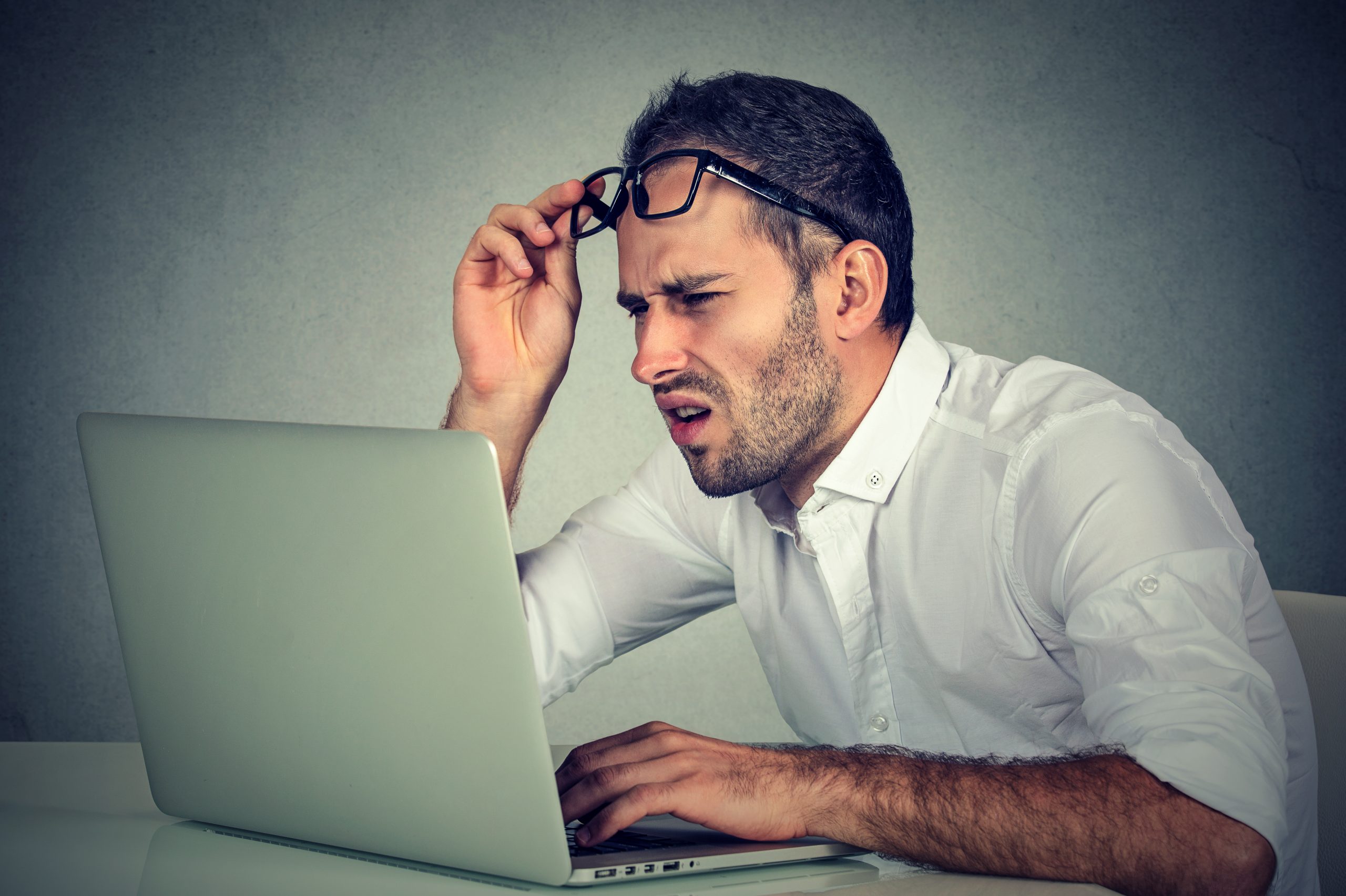 Closeup portrait of business man with glasses looking unhappily at images online of a house that is not ready to sell