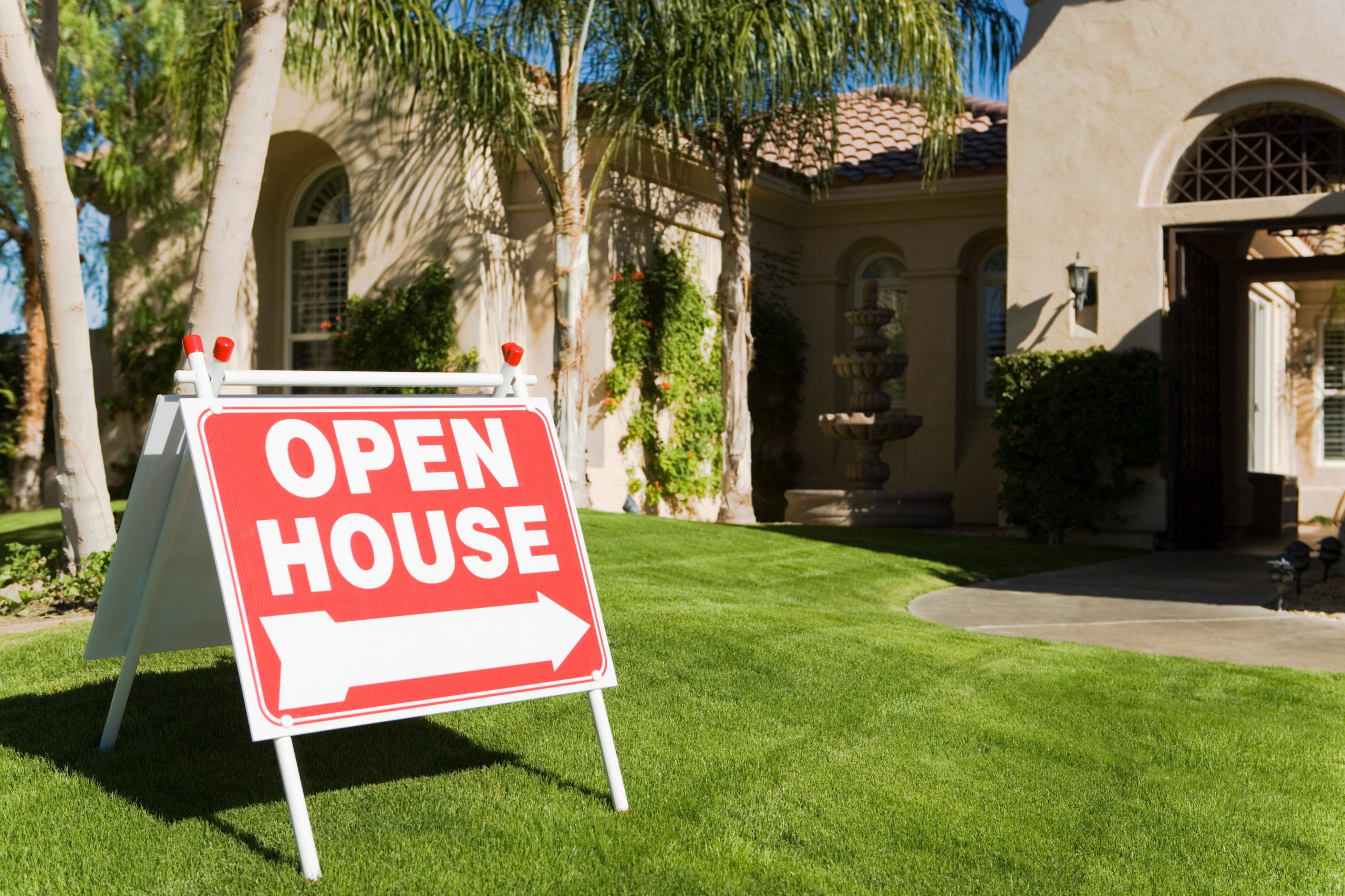 an open house sign on the lawn in front of a house