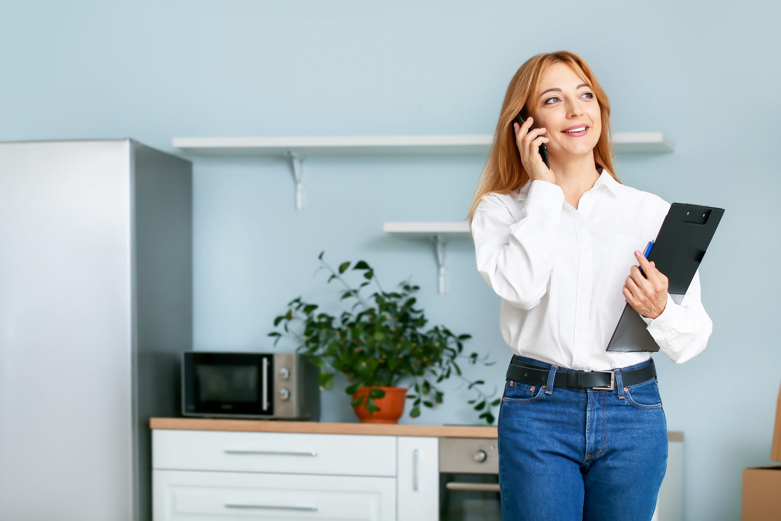 Female real estate agent talking by mobile phone in kitchen open house