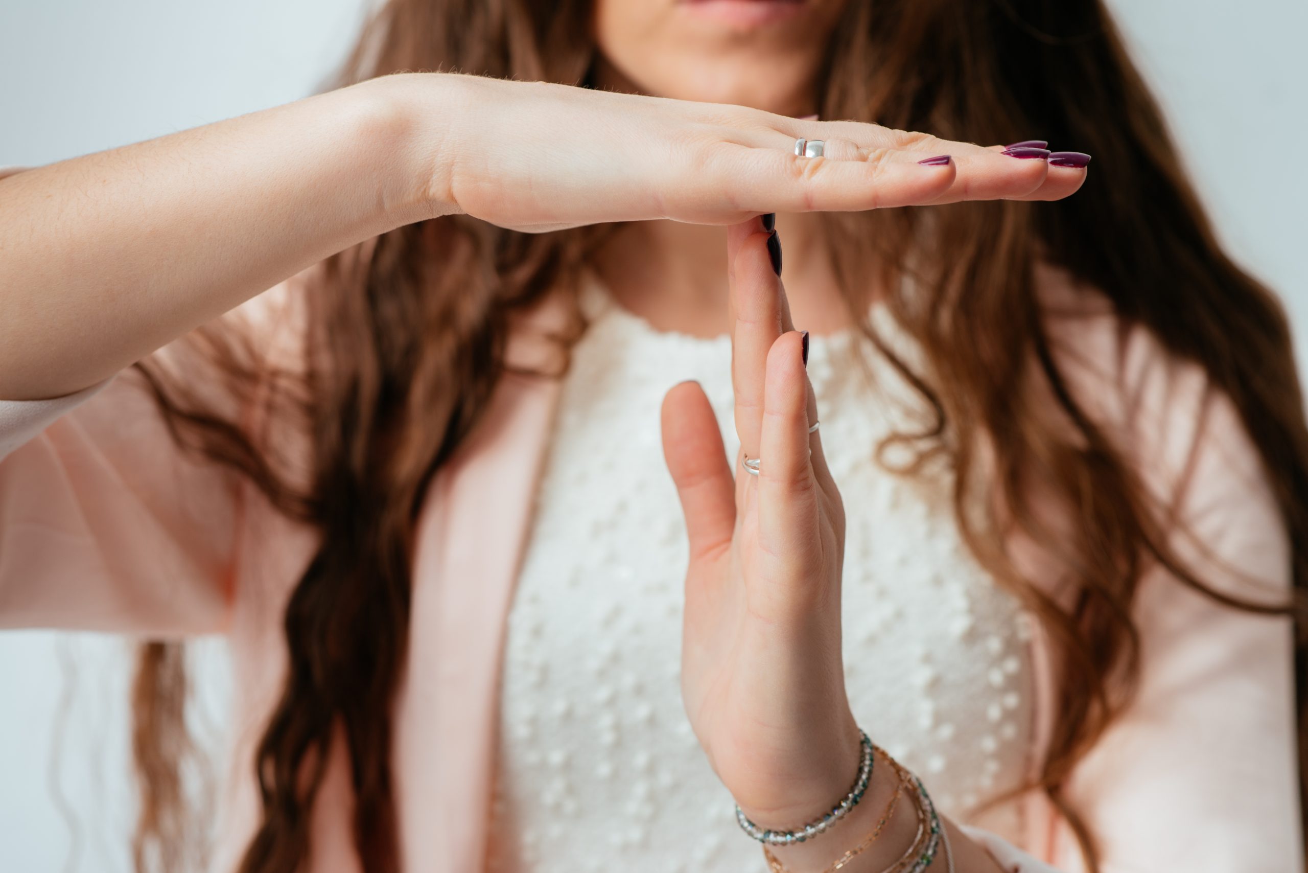 on a gray background a person shows time-out with their hands to illustrate real estate talk to avoid