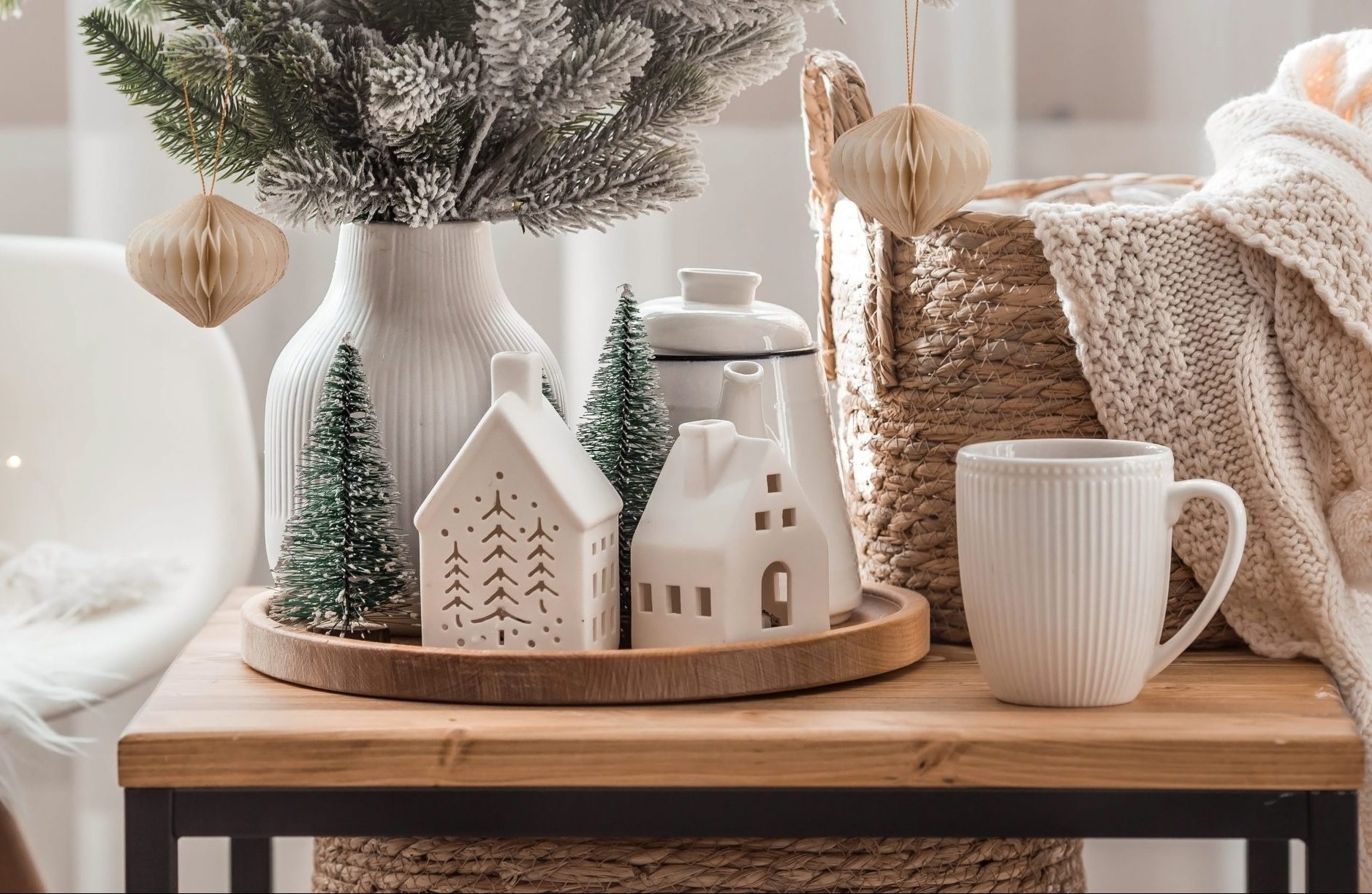 winter home decor ideas; holiday decor on a wood table near a basket with blankets