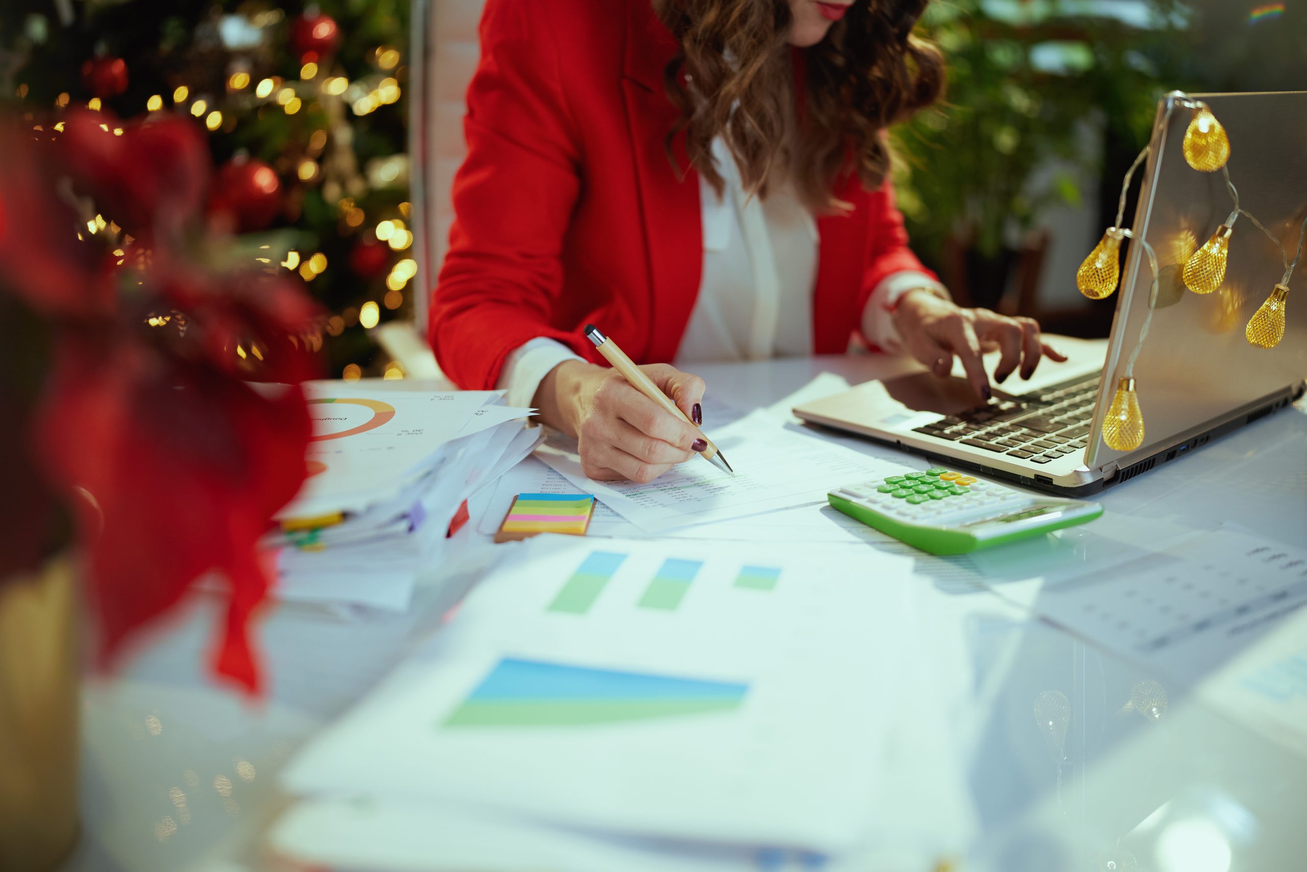 Business owner woman in green office with Christmas tree working on real estate business tips