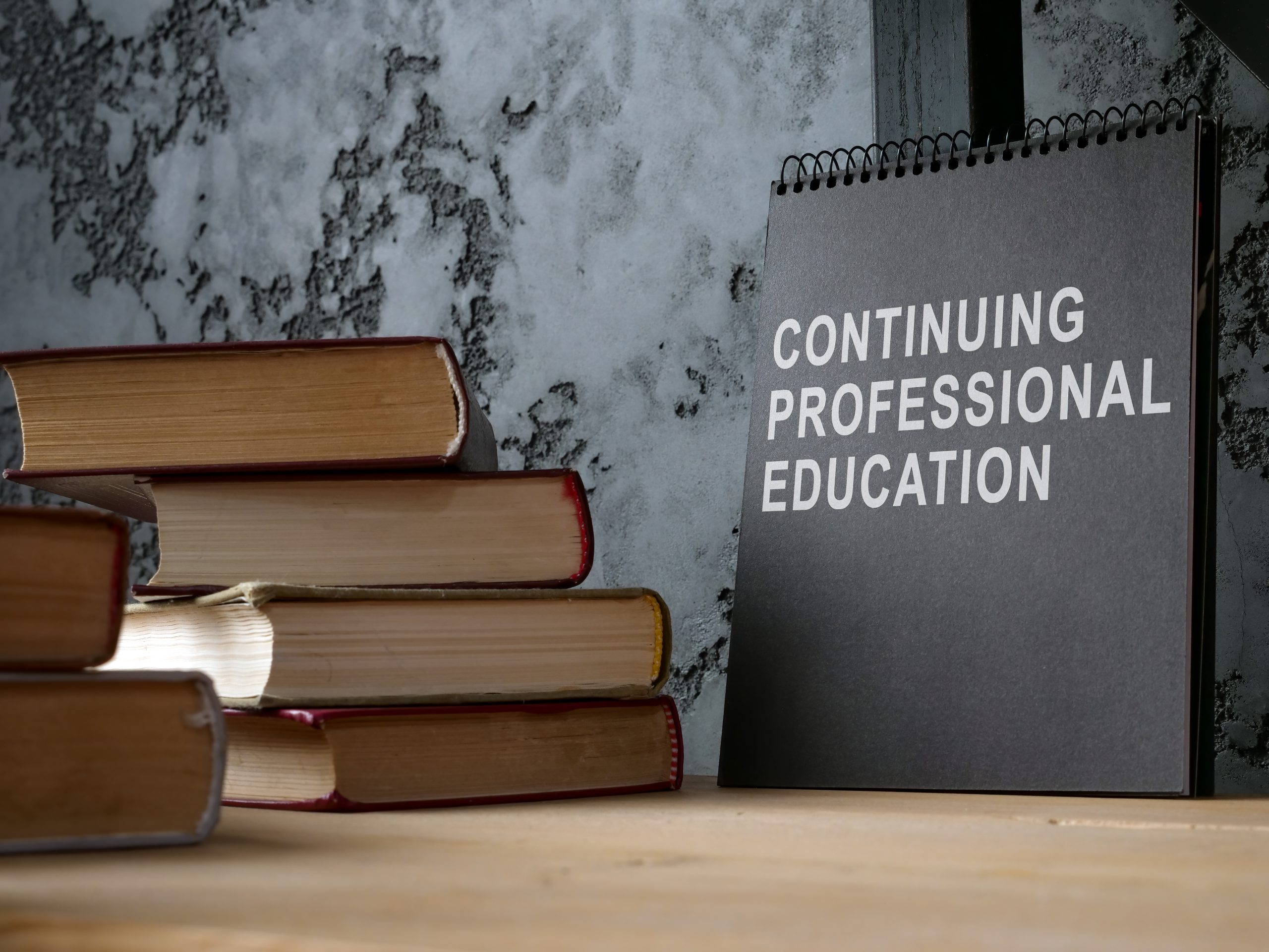 real estate continuing education; continuing professional educated printed on black notepad