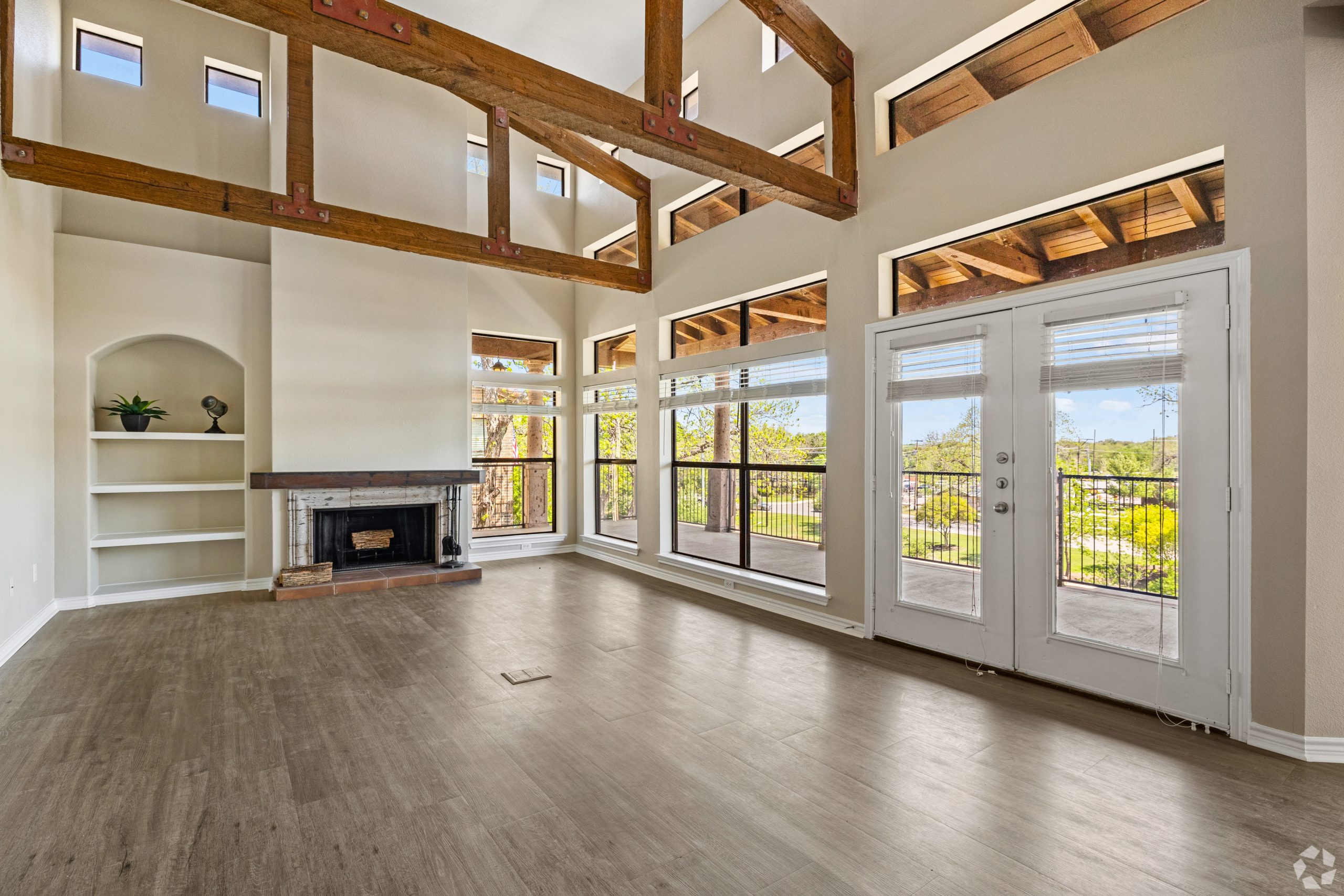 Vacant living space with lofted ceilings and wrap around balcony; before virtual apartment staging